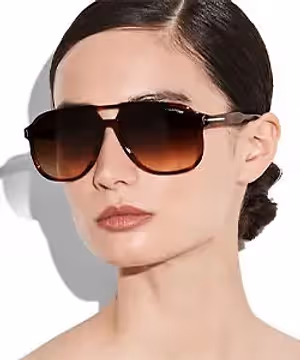 A woman with brown hair wearing sunglasses and makeup