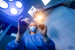 A female doctor in blue scrubs holding a small object in her hands in a hospital room