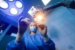 A female doctor in blue scrubs holding a small object in her hands in a hospital room