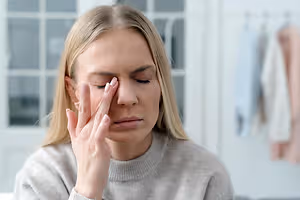Woman with a headache holding her face in a room