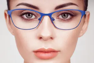 Close-up of a woman's face with blue glasses, her eyes slightly closed, and a slight smile