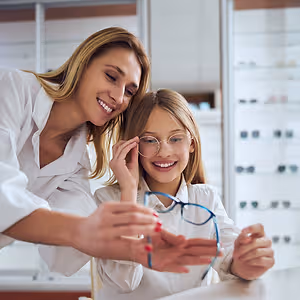 Woman and girl smiling and looking at glasses in an optometrist's office