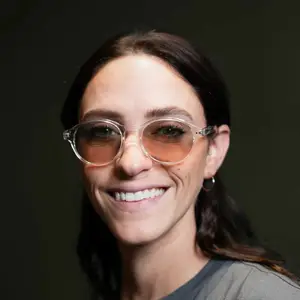Close up of a smiling woman wearing glasses and a gray shirt.