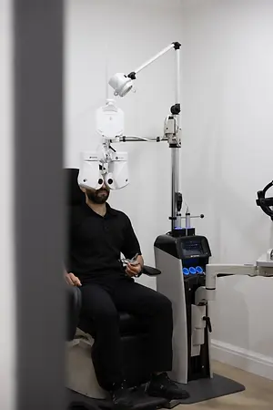 Patient undergoing an eye examination with a phoropter and slit lamp in an optometry exam room