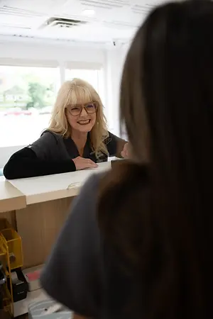 Optometrist speaking with a patient across a reception desk
