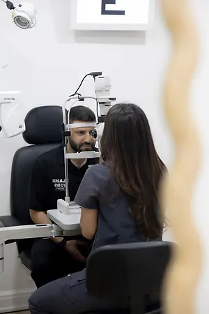 Optometrist examining a patient using a slit lamp in an eye clinic