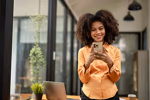 A woman takes a selfie in her office while smiling.