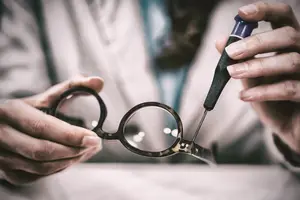 A person is using a screwdriver to adjust a pair of glasses