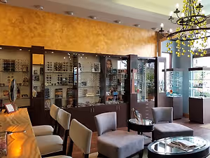 A shop with chairs, tables, and a glass display case with glasses and other items inside
