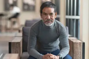 A man sitting on a chair with his hands clasped together