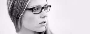 A black and white image of a woman with short hair and glasses looking to the right
