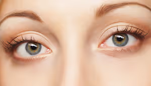 Close-up of a woman's eyes with long eyelashes and a slight redness on the right eye.