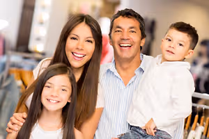A family with a man, a woman, and two kids are smiling and posing for a photo in a clothing store