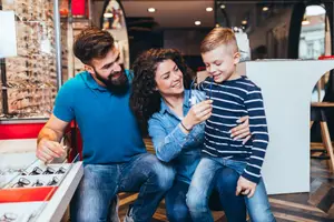 A family is looking at a display of eyeglasses in a shop.