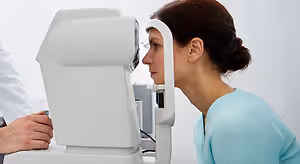 woman with brown hair getting her eye examined by a doctor