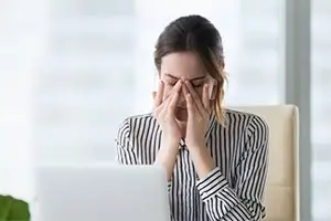 woman sitting in office with hand covering face