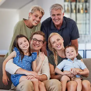A family of six smiling and posing for a photo on a couch in a living room