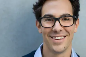 A man with glasses and a smile on his face