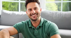 A man sitting on a couch smiling for a photo
