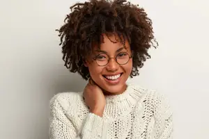 Woman with curly hair and glasses smiling for a photo