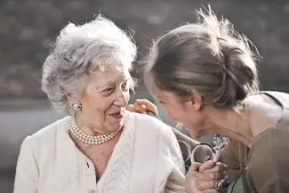 Two elderly women smiling and looking at each other