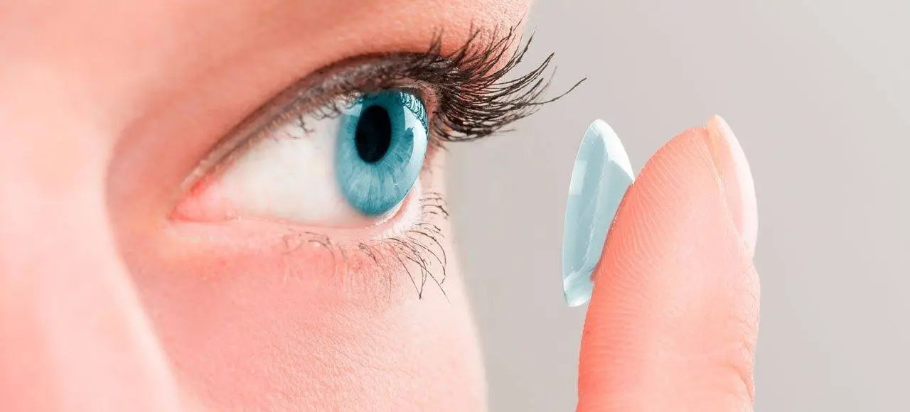 Close-up of a woman placing a contact lens in her eye.