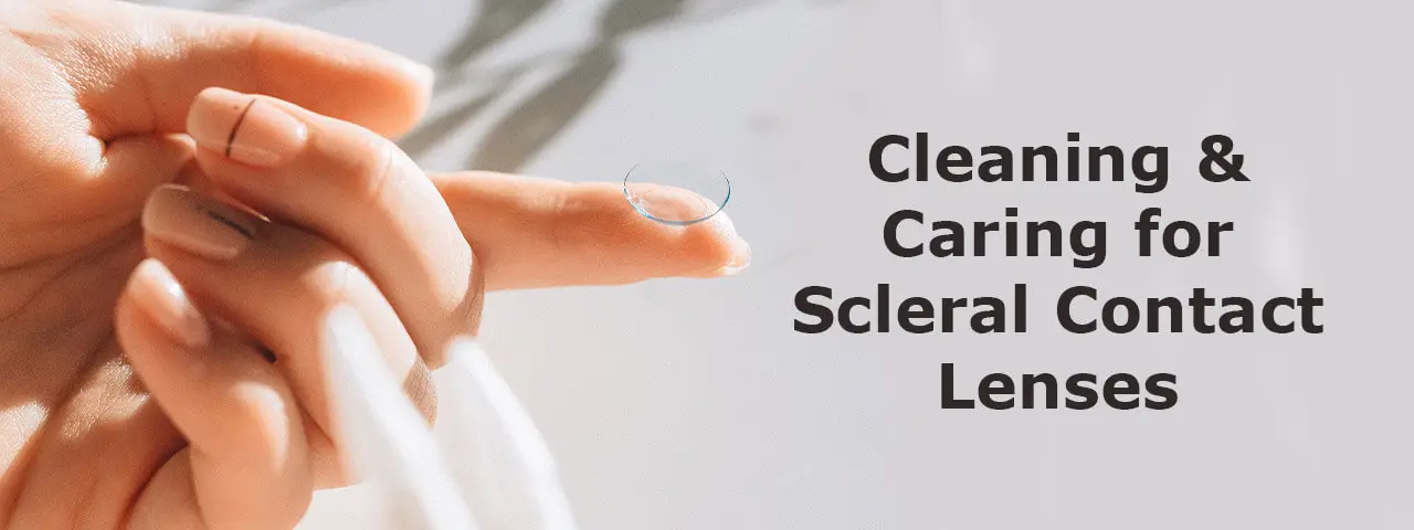 Close-up of a hand holding a scleral lens and applying cleaning solution.