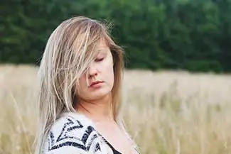 Blonde woman standing in a tall grass field