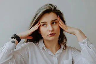 woman holding her head with both hands in pain
