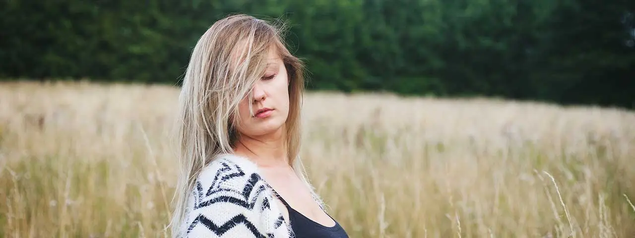 Woman standing in a field with trees in the background