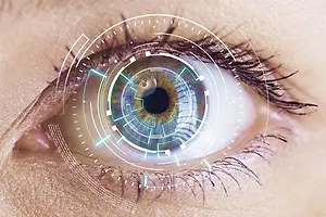 Close up of an eye with a blue and green circular pattern and a blue pupil.