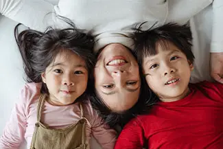 Three children lying on a bed and smiling for a picture