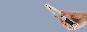 A person holding a white and gray medical device resembling a pen against a blue background