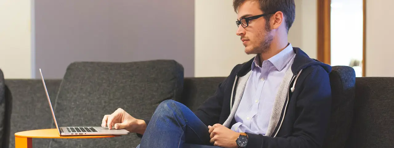 A man sitting on a couch with his laptop