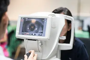 Eye care professional using an autorefractor to examine a patient's eyes