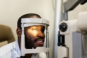 Optometrist examining a man's eye with a slit lamp