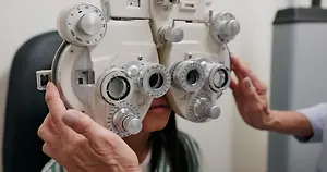 Optometrist adjusting a phoropter during an eye examination