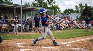 Young baseball player in a helmet swinging at a pitch during a game