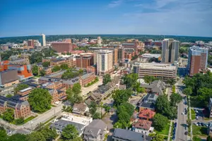 Aerial view of a city with many buildings, trees, and cars on the road.