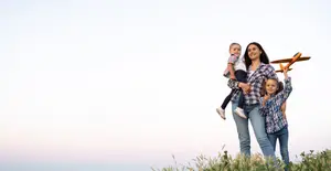 Image of a family of three standing in a field with a toy plane.