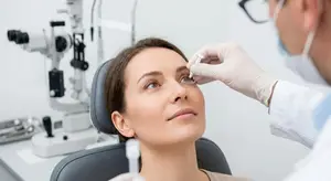 An eye doctor uses a device to check a woman's eye in a clinic setting