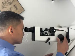 A man in a blue shirt is looking into an eyepiece of a microscope.