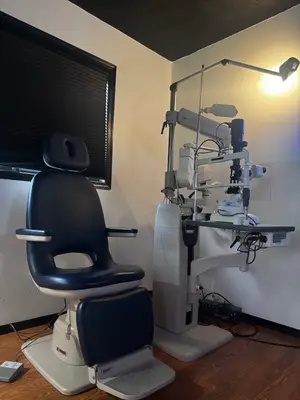 An optometrist's office contains a chair and an ophthalmoscope.