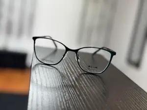 A pair of glasses with a brand name on the side, placed on a wooden table.