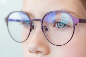 A young girl with glasses looking to her right