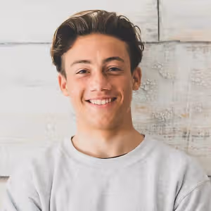 young man smiling in front of a textured white wall