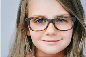 A girl with brown hair and blue eyes wearing glasses