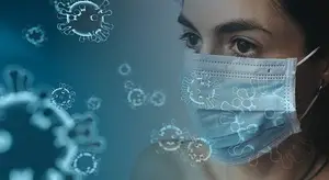 A woman wearing a blue face mask with an illustration of coronavirus floating around her head