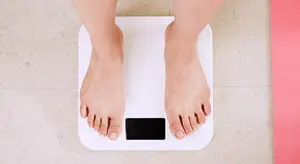 A person standing on a digital scale in a room with a pink mat on the floor
