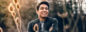 Smiling man standing outside in front of trees